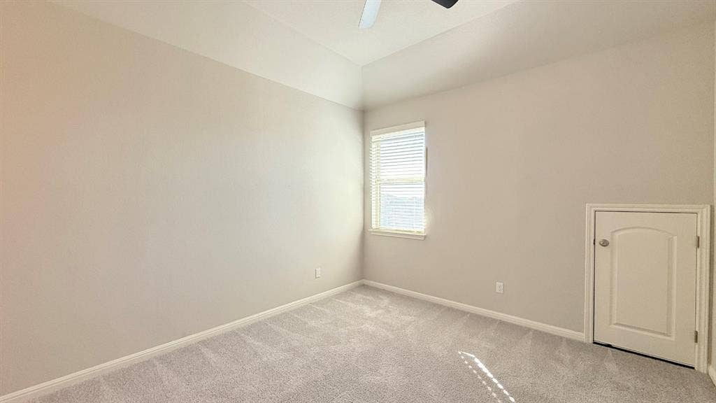 2937 Mossy Springs Drive, Leander, TX 78641 Room featuring a tray ceiling, neutral-toned wall paint, plush carpeting, a single window with blinds, and built-in attic access storage