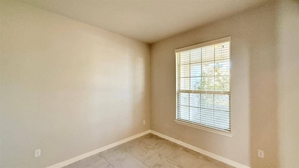 2937 Mossy Springs Drive, Leander, TX 78641 Neutral-toned interior space featuring light-colored wall paint, large-format tile flooring, and a single-hung window with installed horizontal blinds