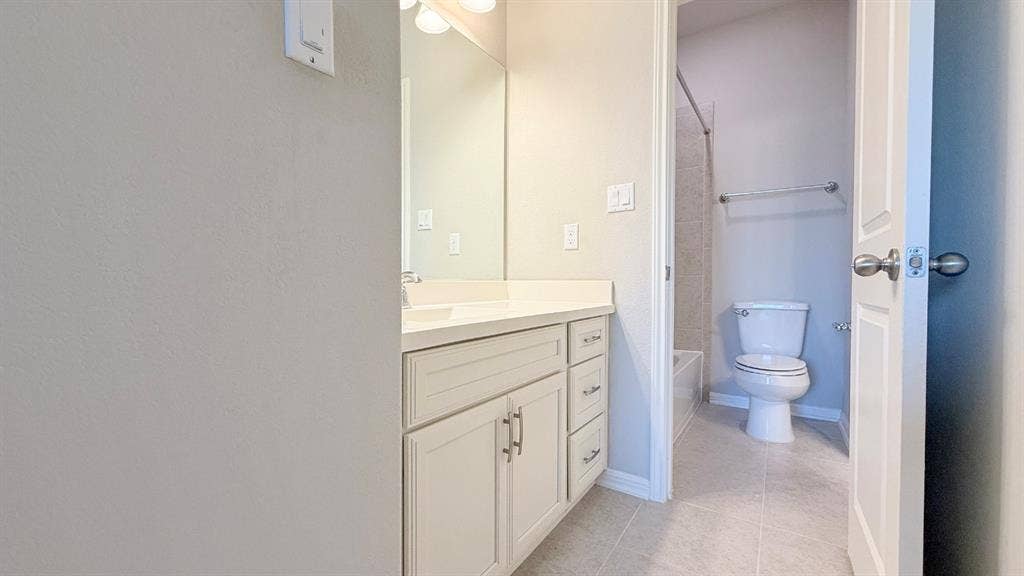 2937 Mossy Springs Drive, Leander, TX 78641 Vanity with stone-finish countertop, undermount sink, shaker-style cabinetry, wall-to-wall mirror, and tile flooring
