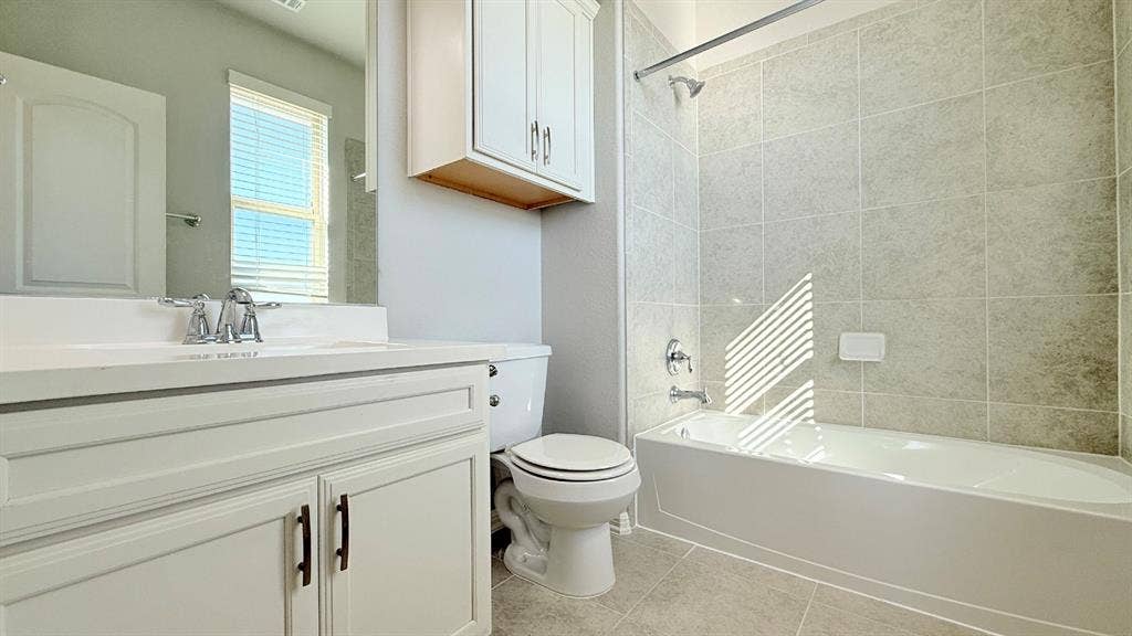 2937 Mossy Springs Drive, Leander, TX 78641 Bathroom featuring a white vanity cabinet with an integrated basin, a wall-mounted medicine cabinet, a tiled shower surround, and a porcelain bathtub
