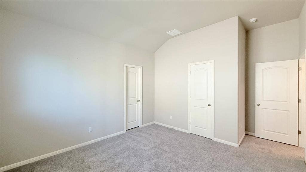 2937 Mossy Springs Drive, Leander, TX 78641 Room featuring vaulted ceilings, neutral wall tones, gray carpeting, and three-panel arched interior doors