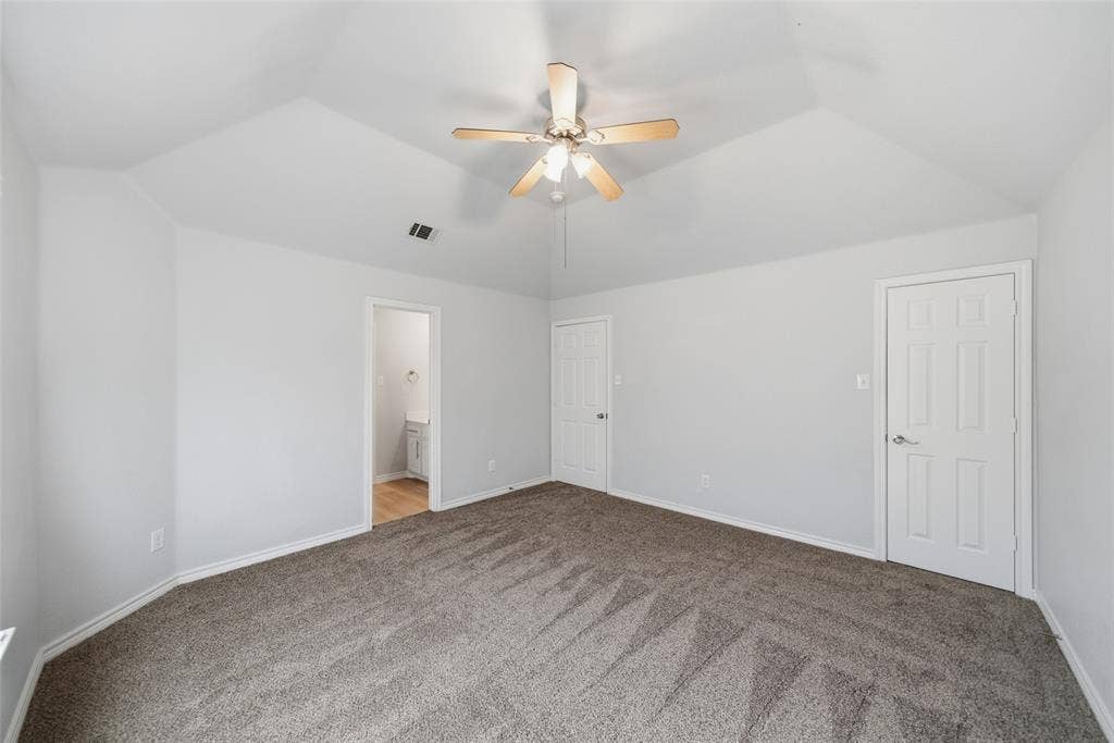 Vaulted ceilings featuring a central ceiling fan with integrated lighting and wall-to-wall carpeting