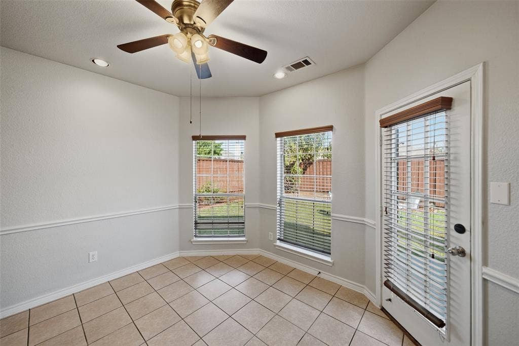 Ceramic tile flooring, bay-style window configuration, recessed lighting, ceiling fan with integrated light fixture, and glass-paneled exterior door