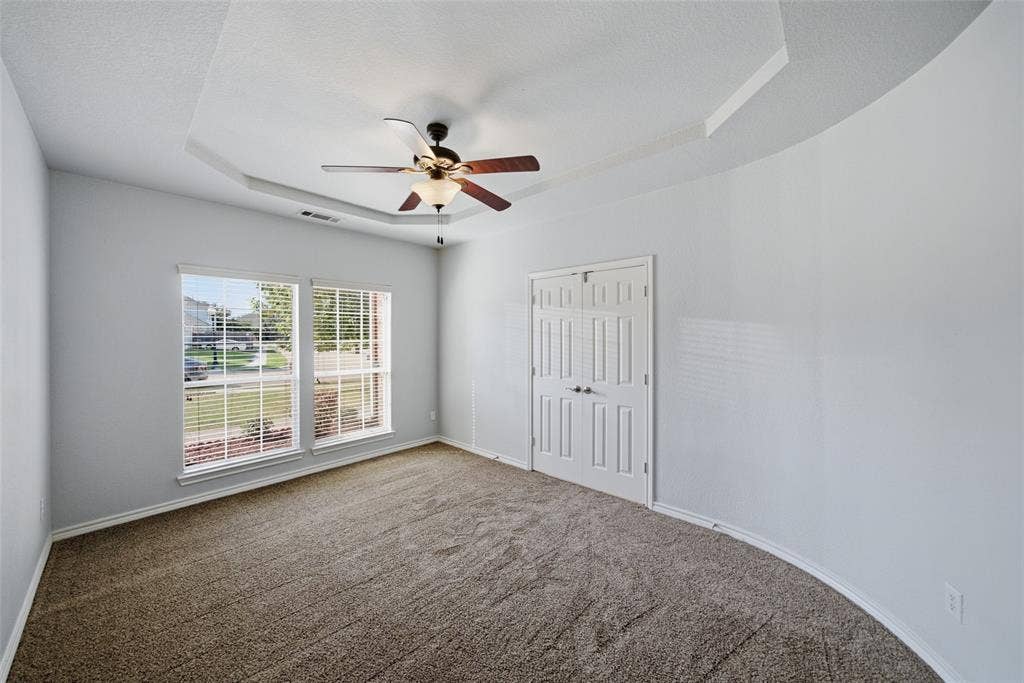 Tray ceiling, dual-pane windows, ceiling fan with light fixture, and double-door closet