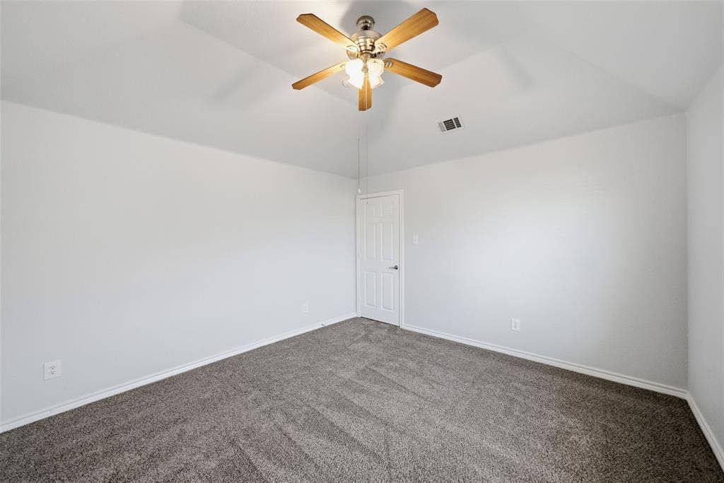 Vaulted ceiling featuring a central wood-finish ceiling fan with integrated lighting and neutral carpeting
