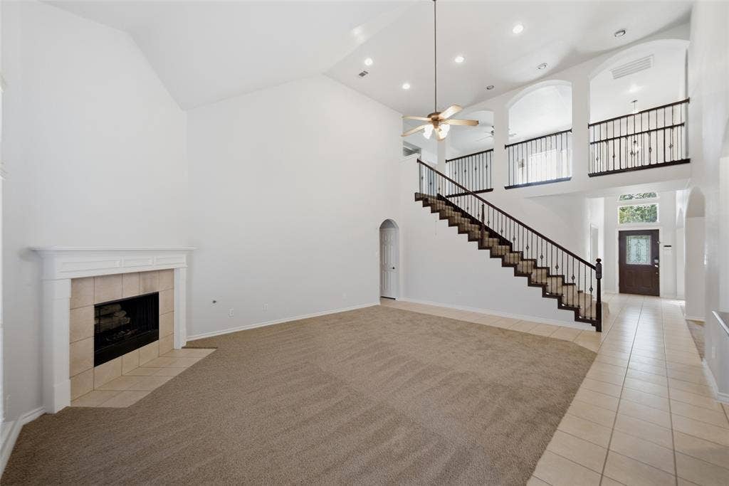 Vaulted ceilings, fireplace with custom-milled mantel, open-staircase with wrought iron balusters, arched architectural detailing, and recessed lighting