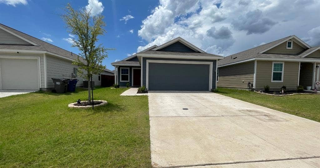 Single-story residence featuring a gray lap-siding exterior, dual-pitched roofline, front-facing two-car garage, and concrete driveway