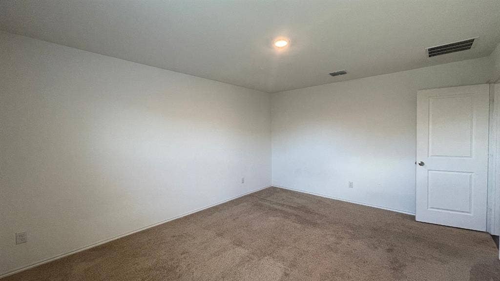 Neutral interior space featuring carpeted flooring, white walls, and a two-panel interior door