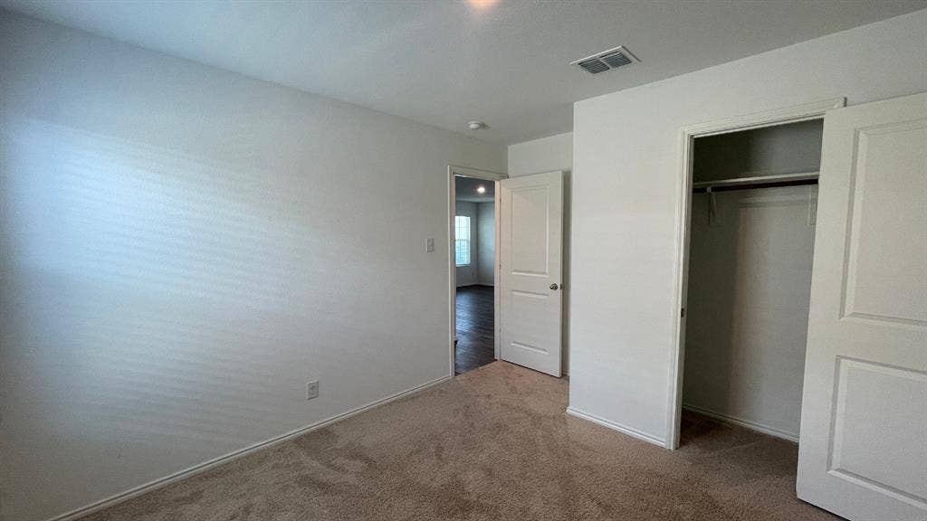 Neutral-toned carpeted flooring, two-panel interior doors, and a built-in closet with overhead shelving