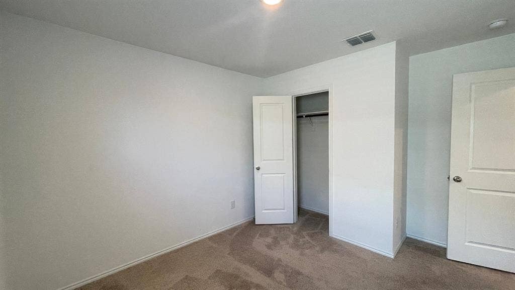 Neutral-toned wall-to-wall carpeting, two-panel interior doors, and a built-in closet with an integrated garment rod