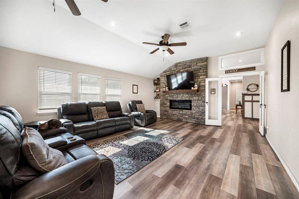 205 Newman Road, Ennis, TX 75119 Vaulted ceilings, wood-finish flooring, and a floor-to-ceiling stone fireplace featuring a recessed electric insert and timber mantel