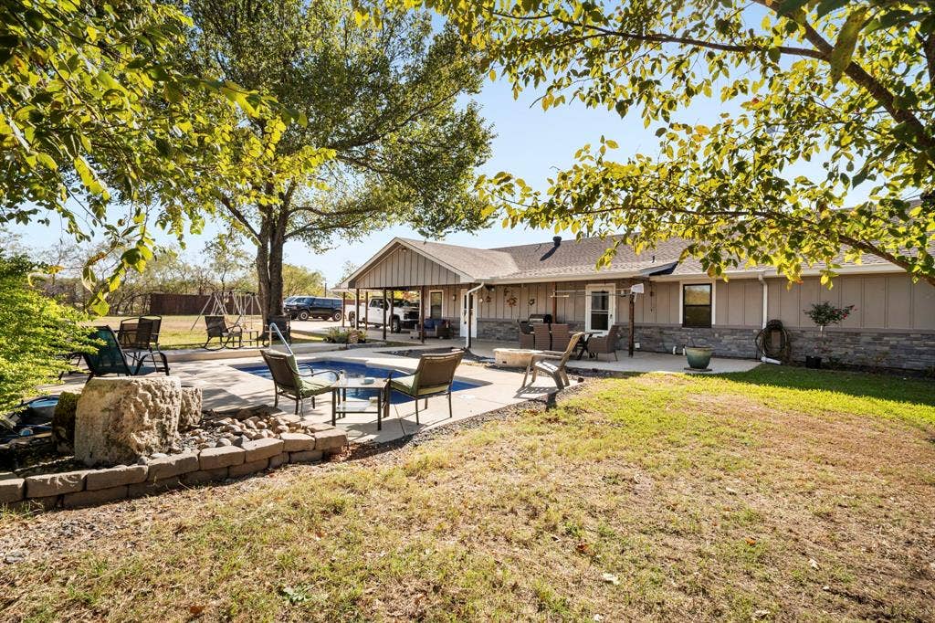 205 Newman Road, Ennis, TX 75119 Exterior featuring an in-ground swimming pool, stone-veneer siding, concrete patio, and a covered porch area