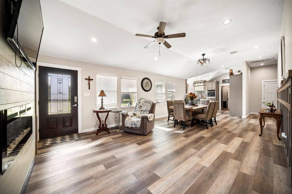 205 Newman Road, Ennis, TX 75119 Open-concept area featuring wood-finish flooring, a wall-mounted electric fireplace, vaulted ceiling, recessed lighting, and a fron