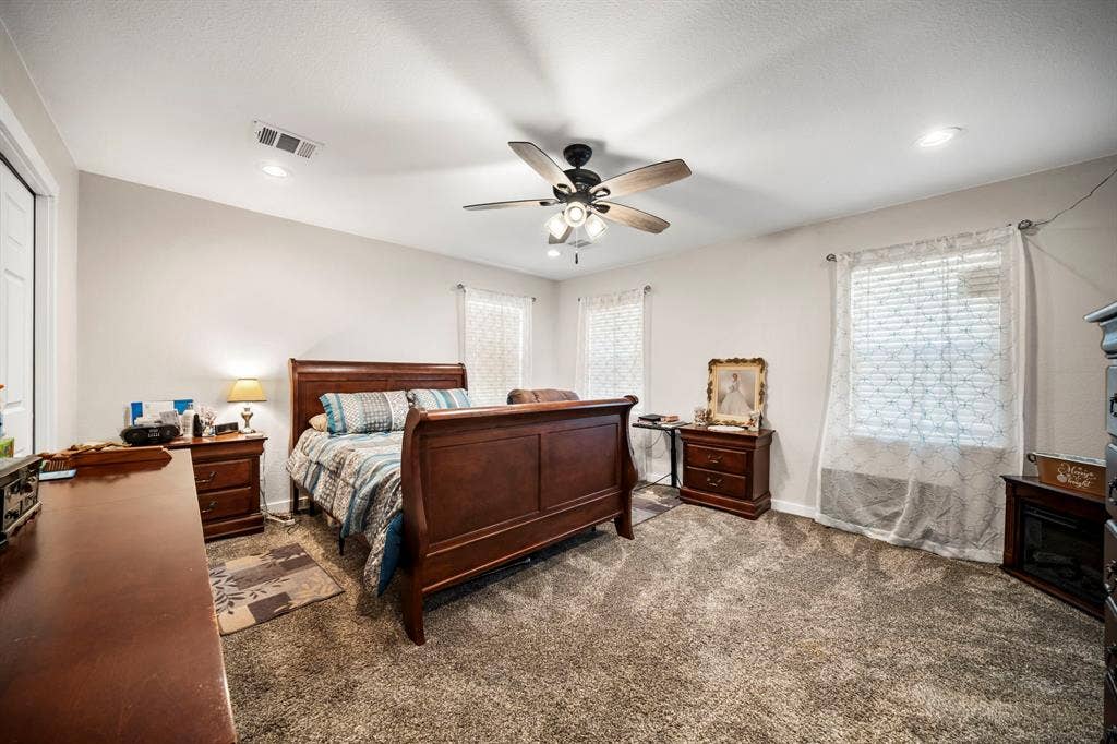 205 Newman Road, Ennis, TX 75119 Neutral-toned bedroom featuring carpeting, multi-window configuration, and a central ceiling fan with integrated lighting