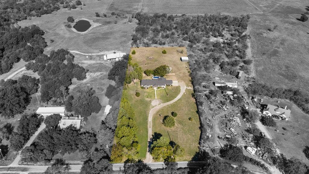 205 Newman Road, Ennis, TX 75119 Aerial view of a sprawling property featuring a paved curved driveway, open acreage, mature trees, and an established residential building