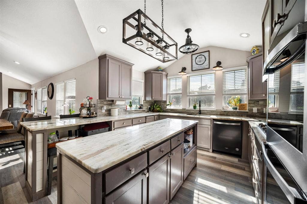 205 Newman Road, Ennis, TX 75119 Kitchen featuring a central island with stone-finish countertops, shaker-style cabinetry, a geometric pendant light fixture, and wood-finish flooring