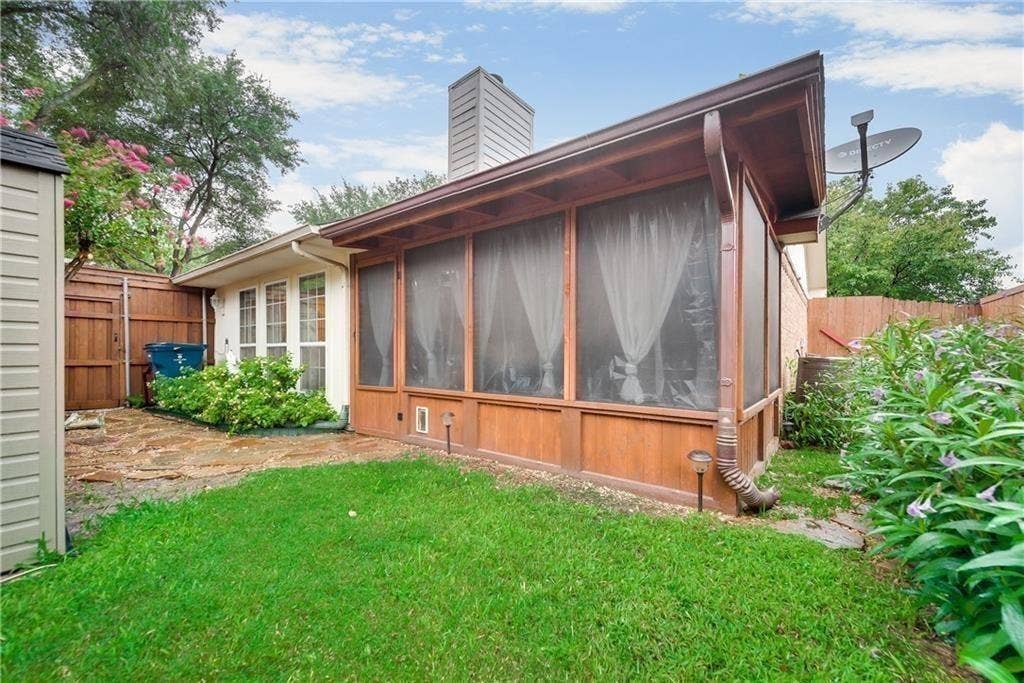 3702 Pulsar Drive, Garland, TX 75044 Screened-in porch with wood-paneled base, exterior lawn, stone-paved walkway, and privacy wood fencing
