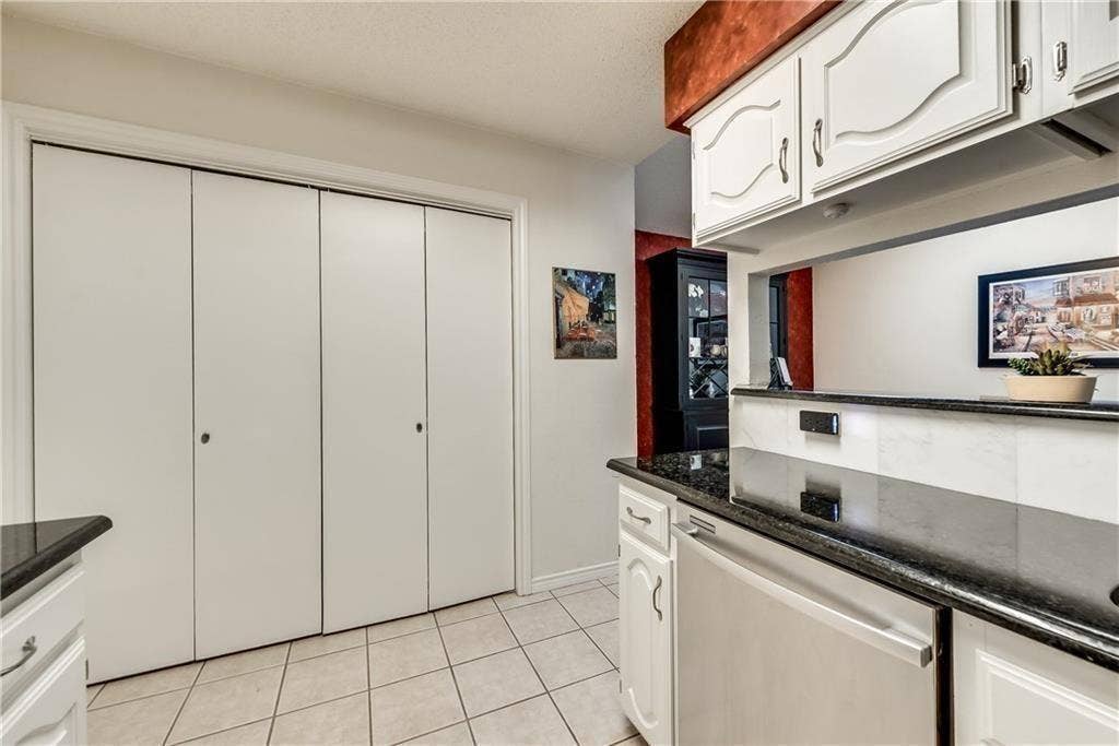 3702 Pulsar Drive, Garland, TX 75044 Kitchen featuring white cabinetry, dark stone-finish countertops, tile flooring, and integrated white bifold closet doors