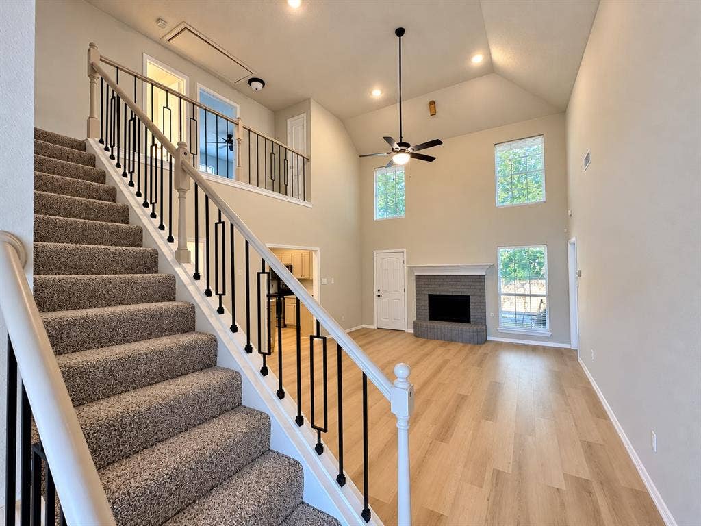 1412 Kaylor Drive, DeSoto, TX 75115 Vaulted ceilings with exposed stairwell, wood-finish flooring, masonry fireplace with raised hearth, and wrought iron baluster railing