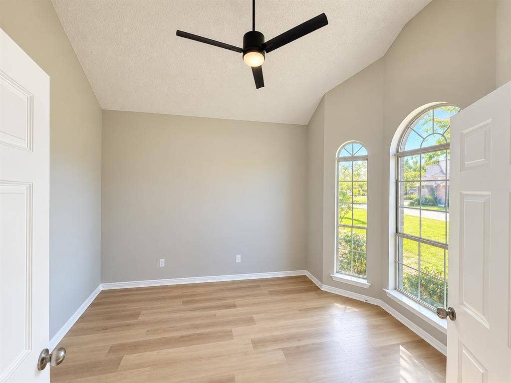 1412 Kaylor Drive, DeSoto, TX 75115 Vaulted ceilings, wood-finish flooring, matte black ceiling fan with integrated lighting, and dual arched windows