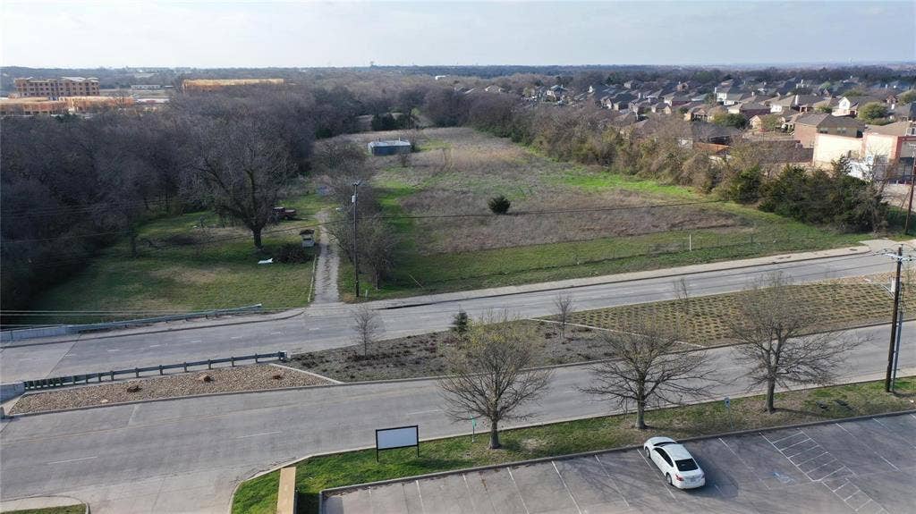 Aerial view of a large, undeveloped lot featuring a mix of cleared land and mature trees