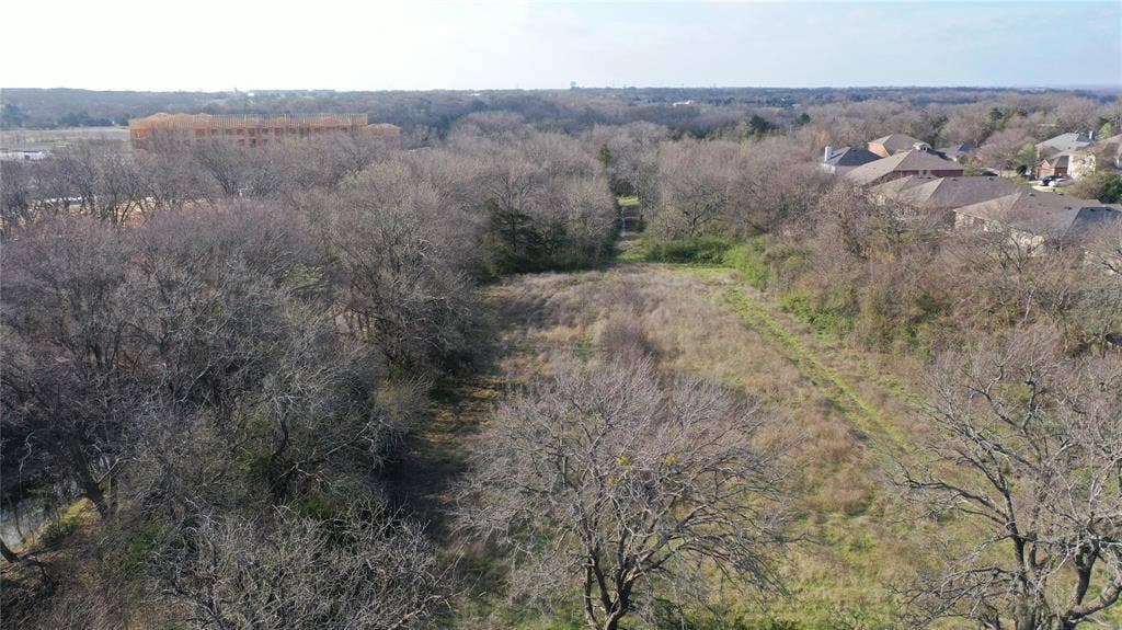 Expansive parcel with mature trees and a cleared central area, offering views of surrounding development and residential properties