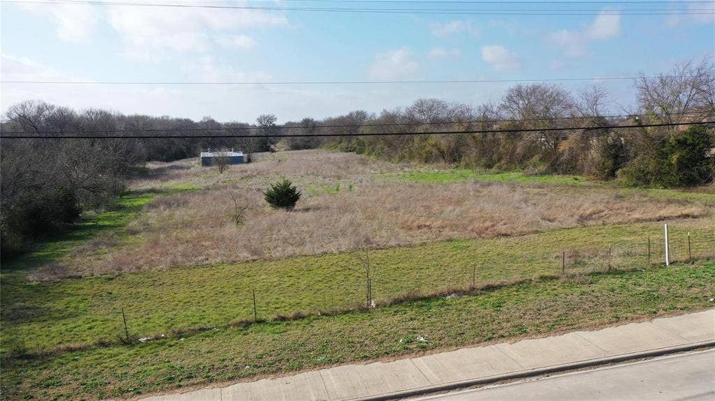 The property offers expansive open land with varying vegetation and a distant structure