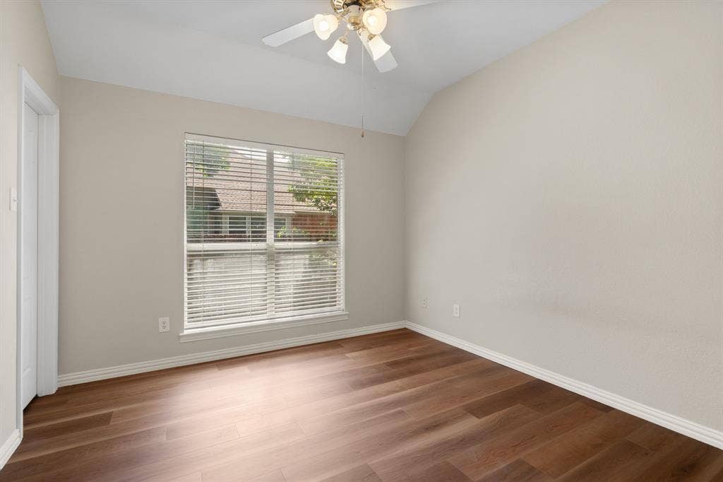 Spare room featuring lofted ceiling, ceiling fan, and wood finished floors