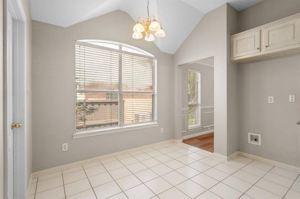 Unfurnished dining area featuring lofted ceiling, a chandelier, and light tile patterned floors