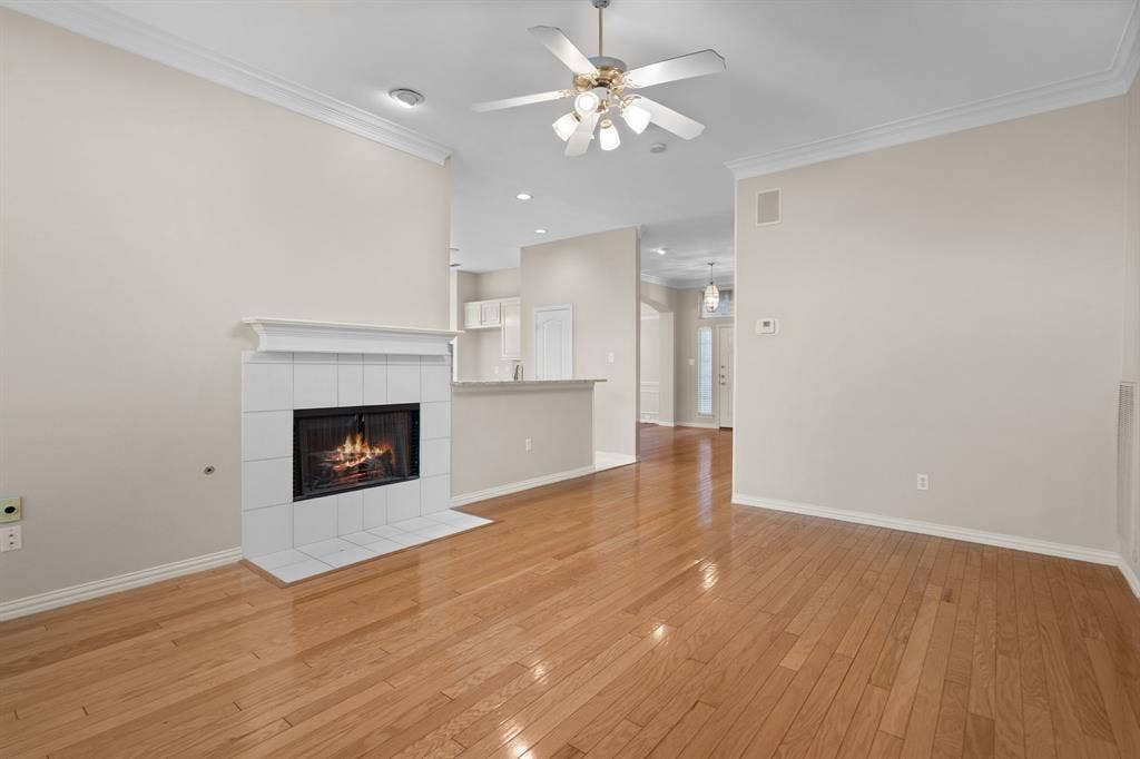 Unfurnished living room with a tile fireplace, a ceiling fan, light wood-style floors, ornamental molding, and recessed lighting