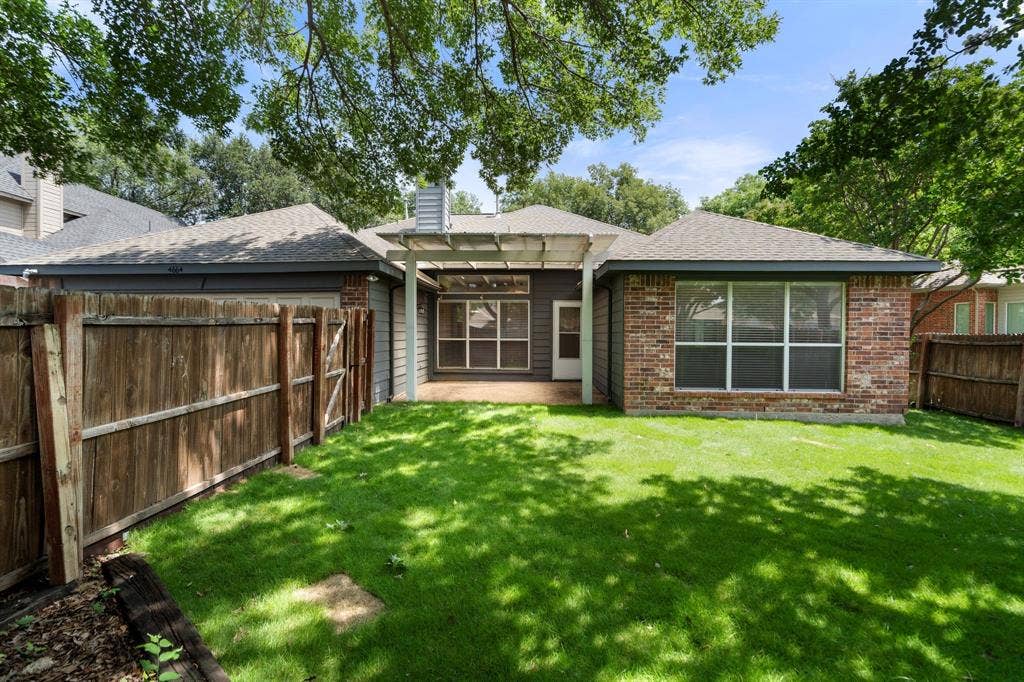 Rear view of house featuring a fenced backyard, a chimney, brick siding, a patio area, and a shingled roof