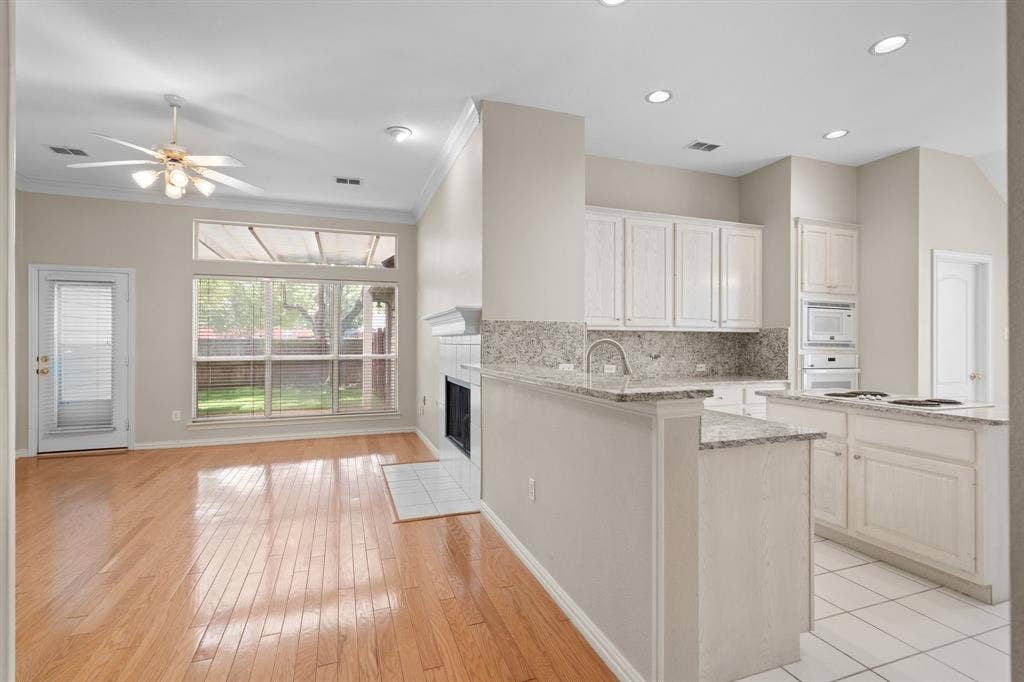Kitchen featuring white appliances, ornamental molding, light wood-style floors, a fireplace, and ceiling fan