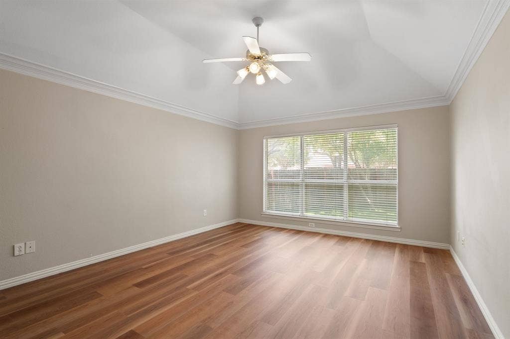 Empty room with vaulted ceiling, light wood-type flooring, ceiling fan, and ornamental molding