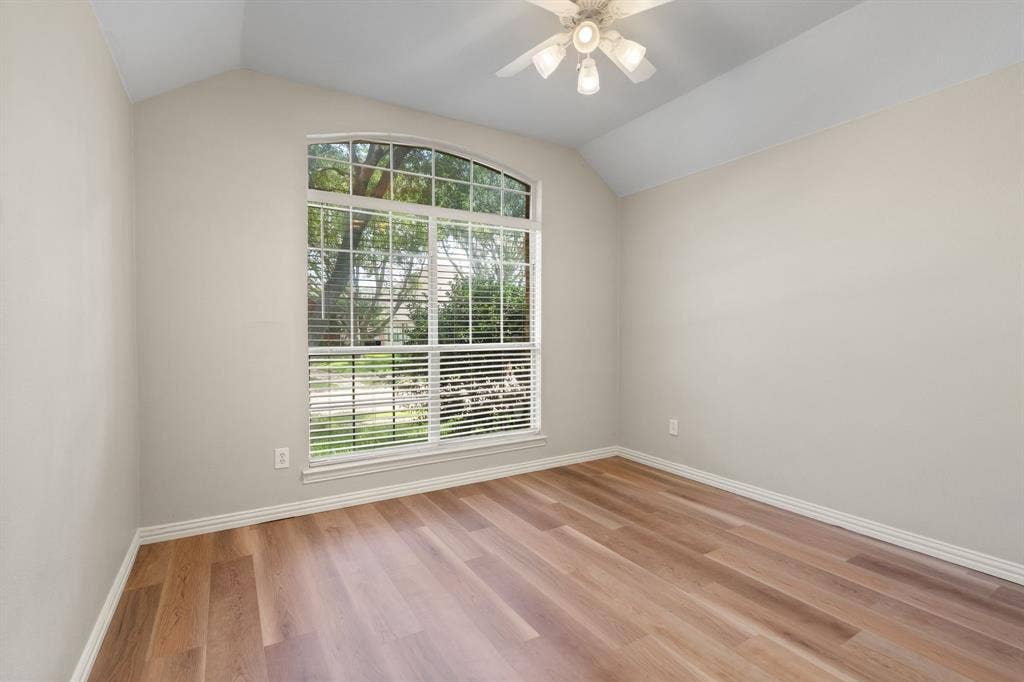 Empty room with plenty of natural light, vaulted ceiling, light wood finished floors, and ceiling fan