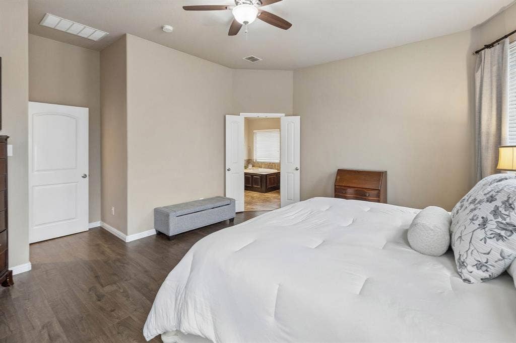 Another view of the primary bedroom highlights the elegant French doors leading into the private ensuite bathroom.