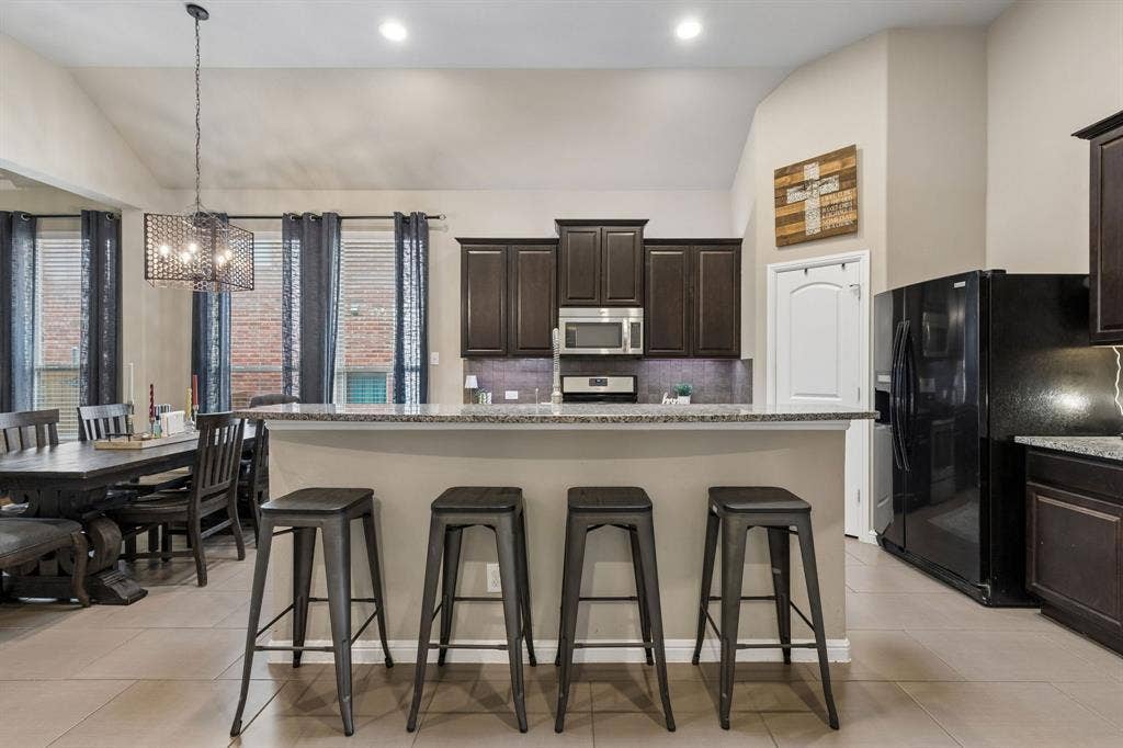 Another view of the kitchen highlights the spacious breakfast bar, recessed lighting, and adjacent dining area just to the left.