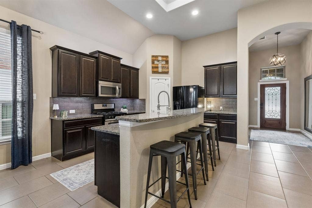 The kitchen features beautiful 42-inch stained cabinets, granite countertops, stainless steel appliances, tile flooring, and plenty of storage space.