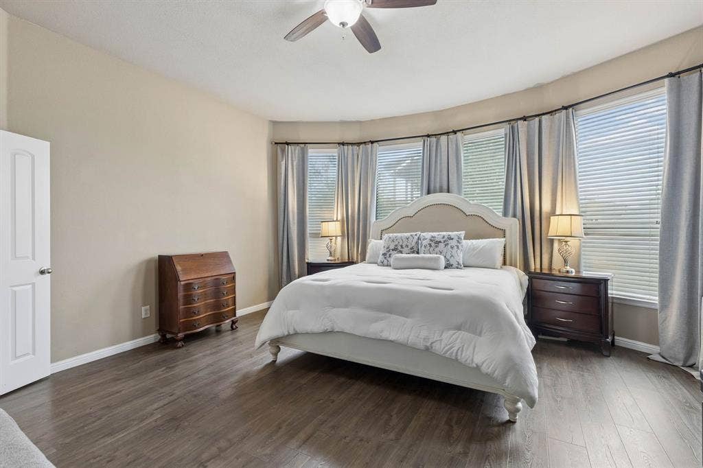 The spacious primary bedroom features large windows that fill the room with natural light, LVP flooring, a ceiling fan, and a private ensuite bath.