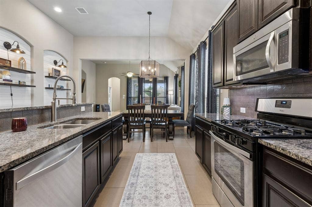 Another view highlights the stainless steel appliances, gas range, and convenient open access to the dining area.