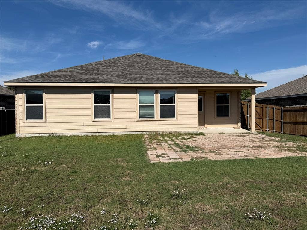 212 Belford Street S, Anna, TX 75409 Rear elevation featuring horizontal lap siding, a hipped roof, covered patio area, concrete paver patio, and wood privacy fencing