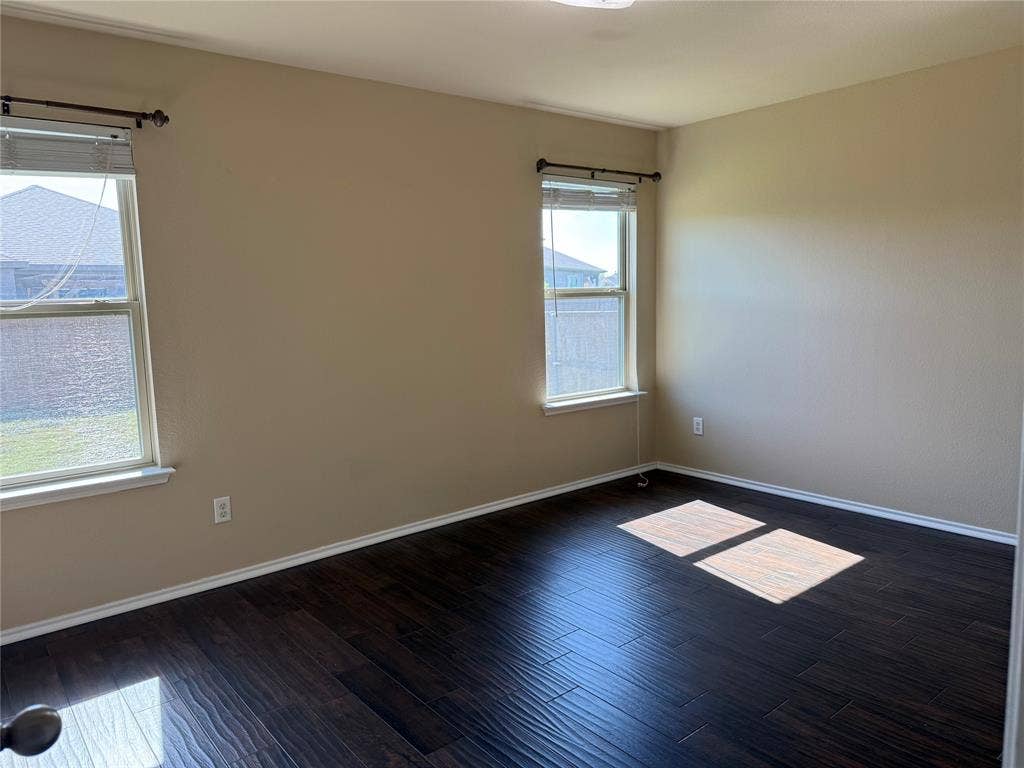 212 Belford Street S, Anna, TX 75409 Room featuring dark wood-finish flooring, neutral-toned walls, and two double-hung windows with installed curtain rods