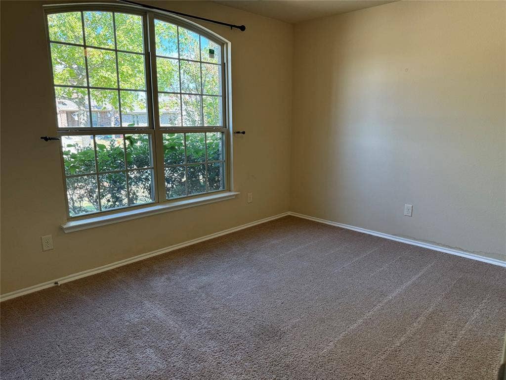 212 Belford Street S, Anna, TX 75409 Room featuring neutral wall tones, wall-to-wall carpeting, and a large arched window with grid detailing