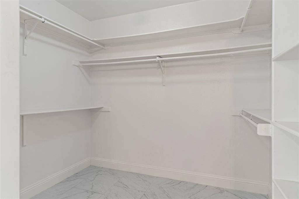 4128 Woodenrail Lane, Irving, TX 75061 Walk-in closet featuring multi-level built-in shelving, white overhead hanging rods, and patterned tile flooring