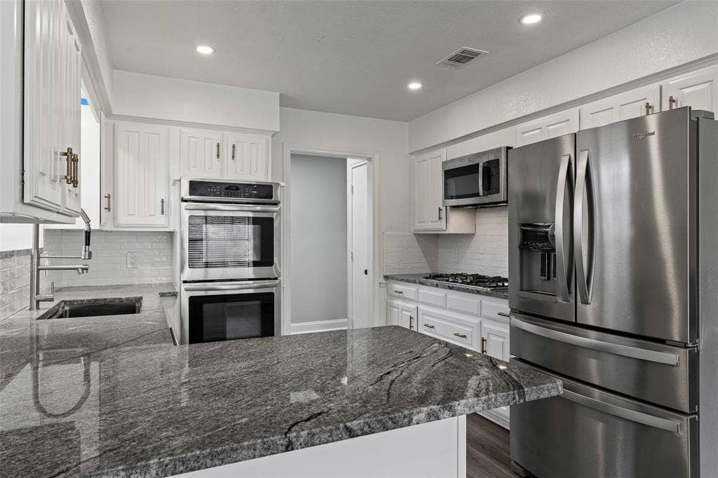 4128 Woodenrail Lane, Irving, TX 75061 Kitchen featuring white cabinetry, granite countertops, stainless steel double wall ovens, gas cooktop, and a stainless steel french-door refrigerator