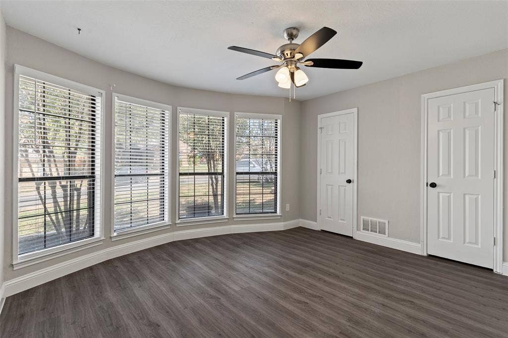4128 Woodenrail Lane, Irving, TX 75061 Room featuring wood-finish flooring, a four-panel bay window configuration, and a multi-blade ceiling fan with integrated lighting