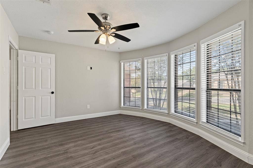4128 Woodenrail Lane, Irving, TX 75061 Bay window featuring four windows, wood-finish flooring, brushed nickel ceiling fan with integrated lighting, and a six-panel interior door