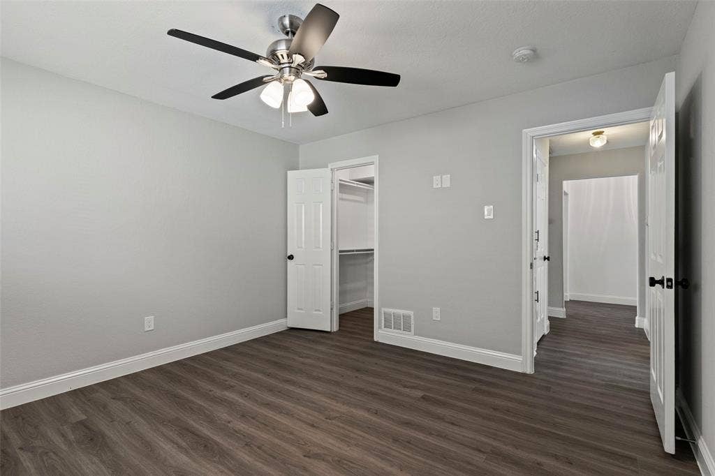 4128 Woodenrail Lane, Irving, TX 75061 Neutral-toned interior featuring wood-finish flooring, a multi-blade ceiling fan with integrated lighting, a six-panel door, and a built-in walk-in closet