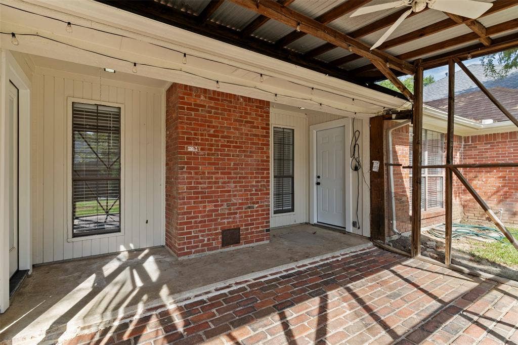 4128 Woodenrail Lane, Irving, TX 75061 Screened-in porch featuring a brick-paved floor, exposed wood-beam ceiling with a mounted ceiling fan, and a red brick exterior accent wall