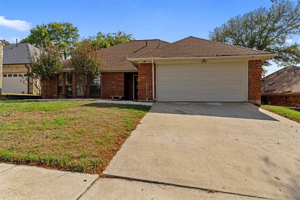4128 Woodenrail Lane, Irving, TX 75061 Single-story brick exterior featuring a composite shingle roof, two-car garage, and concrete driveway
