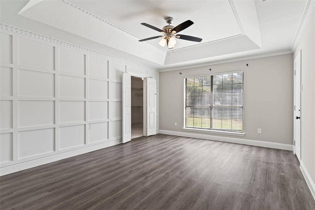 4128 Woodenrail Lane, Irving, TX 75061 Interior space featuring a recessed tray ceiling, wood-finish flooring, decorative wall molding, and a central ceiling fan with integrated light fixture